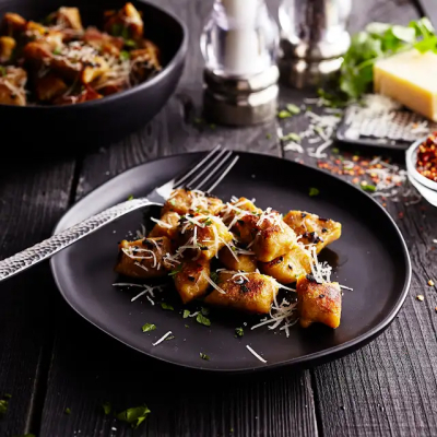 Fresh gnocchi on black plate with fork